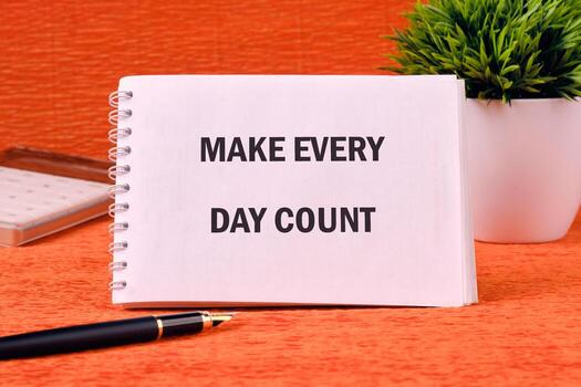 Concept words MAKE EVERY DAY COUNT on a spiral notebook on an orange background photo