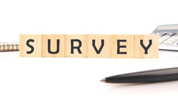 Wooden blocks neatly form the word survey, surrounded by a calculator, a pen, and a notepad in a clean office space, suggesting research or data collection activities photo