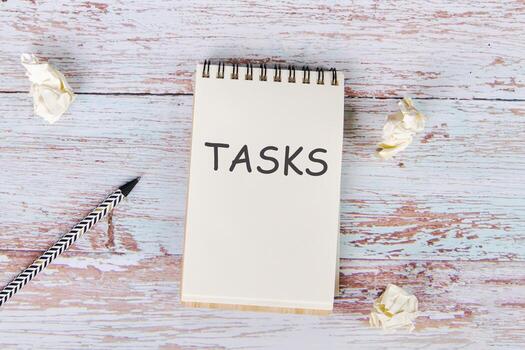 The text of the assignment is written in a notebook lying next to crumpled paper and a pencil photo