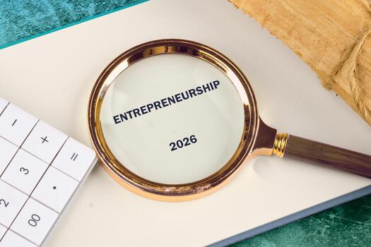 A close-up view features a magnifying glass emphasizing the word entrepreneurship for 2026 alongside a calculator and a wooden block, symbolizing financial planning and analysis photo