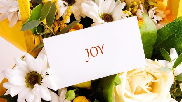 A vibrant bouquet filled with white daisies and yellow roses features a card displaying the word joy. This beautiful arrangement radiates happiness and warmth photo