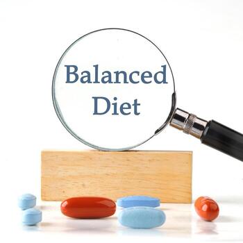 Balanced Diet text written it manifested itself in a magnifying glass standing on a wooden bar. The aspect ratio of the photo is 1 to 1