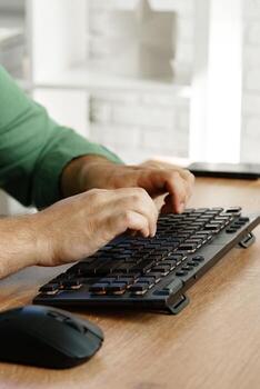 Hands typing on a keyboard beside a computer mouse during a work session at home photo