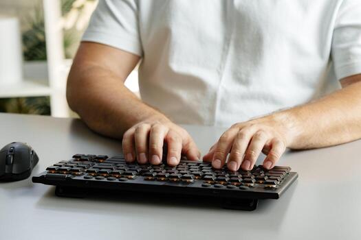 Individual typing on a keyboard while seated at a desk in a modern workspace photo