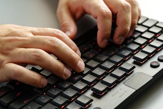 Hands typing on a black keyboard while working on a computer during daytime photo