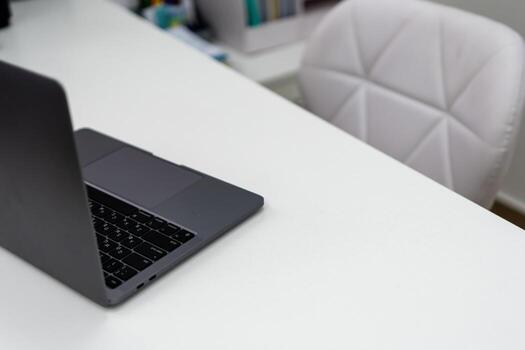 Laptop, workspace, desk. Modern dark grey notebook computer open on a clean white table with copy space photo