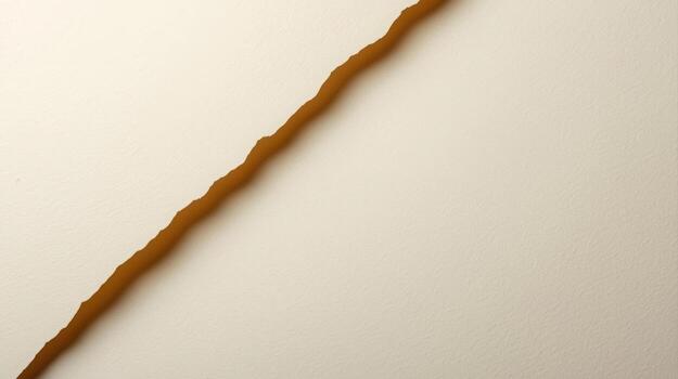 A close up shot shows a long and winding crack running diagonally across a textured white surface, creating a strong contrast in color. photo