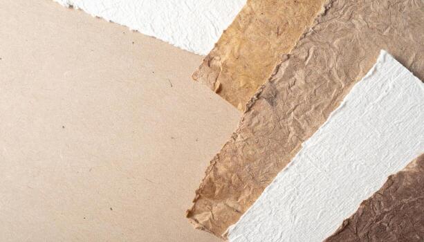 Assorted handmade papers with rough edges are layered on a beige background creating texture and a natural aesthetic for design projects. photo