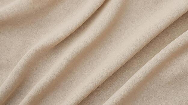 The soft beige fabric drapes elegantly with gentle folds creating a subtle texture and warm neutral background for fashion or design projects. photo