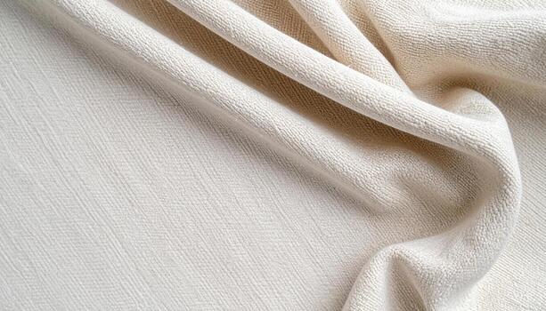 An undyed natural cotton fabric is draped elegantly showing its soft, woven texture in a close-up studio shot highlighting detail and folds. photo