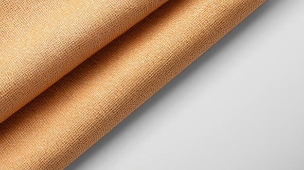 Close up photograph of textured light brown fabric draped diagonally on a white background, creating soft shadows with a clean, modern aesthetic. photo