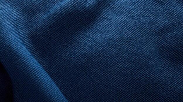 Close-up of a textured dark blue knitted fabric with subtle folds creating an abstract and visually interesting textile background design. photo