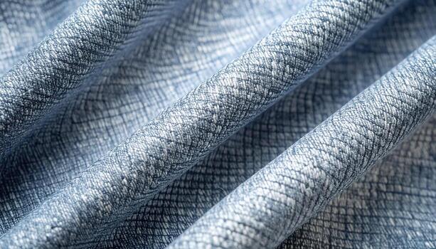 Gently folded blue fabric with a subtle crosshatch pattern creates soft undulating curves and delicate shadows in the light on its texture. photo