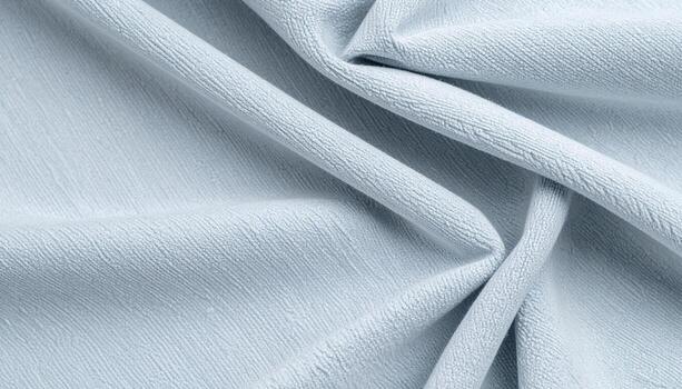 Light blue fabric drapes softly, creating a subtle texture and highlighting delicate folds with a gentle interplay of light and shadow. photo