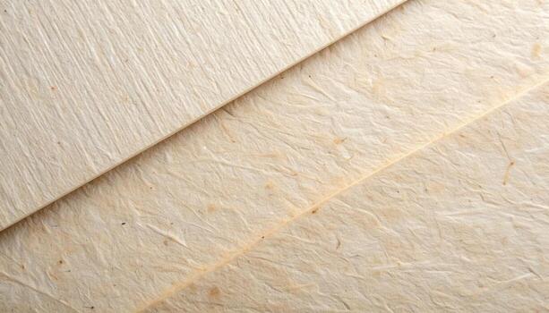 Soft light illuminates the textured surface of overlapping handmade paper sheets, revealing subtle variations in color and fiber composition. photo
