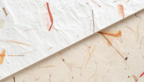 Two different handmade papers crafted with delicate flower petals are placed diagonally to show the subtle differences in texture and color. photo