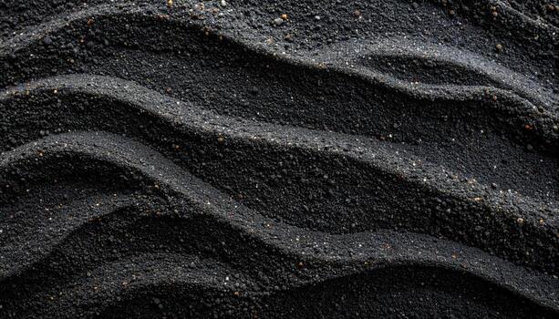 The undulating patterns in the dark, gritty texture of black sand create a visually striking and naturally abstract scenic background. photo