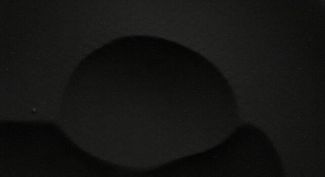 An abstract dark and textured background shows a mysterious rounded shape emanating an aura of darkness and subtle light in minimalist style. photo