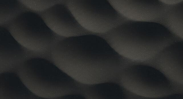 A textured dark gray surface presents a visually interesting pattern of undulating waves, creating a soft and flowing abstract background effect. photo