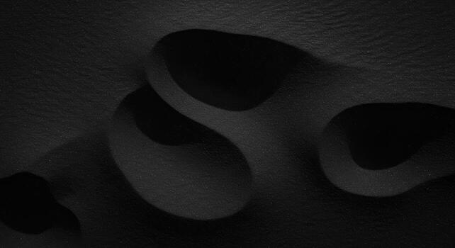 Abstract monochrome landscape features smooth, curved shapes and deep shadows, creating a dramatic and mysterious visual texture in black. photo