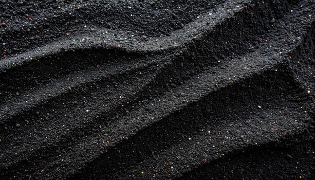 The undulating pattern of the black sand creates a textured surface with subtle highlights and shadows, a visually interesting dark background. photo