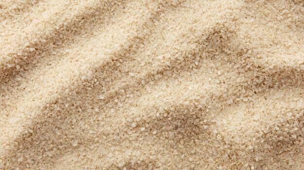 Close-up photograph displaying rippled beige sand with detailed textured grains, offe a warm, natural, and inviting beachy atmosphere. photo