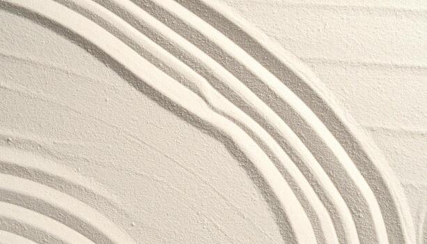 Curved patterns are delicately raked into fine, light colored sand, creating a textured and calming minimalist abstract background design. photo