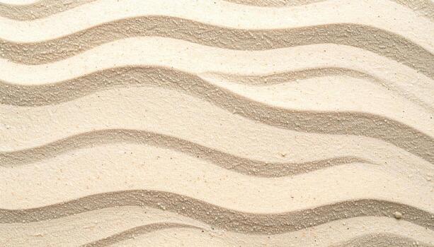 An overhead shot shows a calming pattern of rhythmic sand waves rippling across a sunlit beach landscape, creating an abstract texture surface. photo