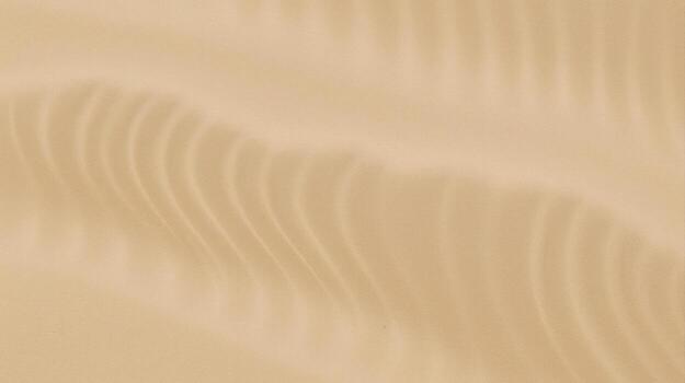 The undulating patterns of wind-swept sand create a mesmerizing abstract texture in the serene and sun-drenched desert landscape. photo