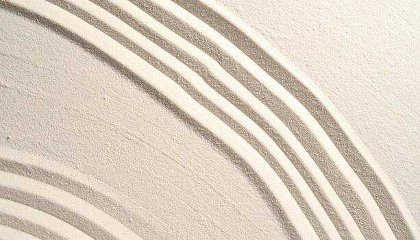 Top down view shows raked white sand with curving parallel lines forming a minimalist zen garden pattern offe peace and tranquility. photo