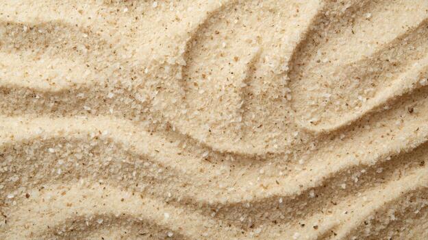 Close up of rippled sand with a natural wave pattern glistening in the sunlight on a beach providing a textured neutral background element. photo