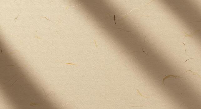 Warm tan textured paper background is highlighted by soft light filte through, casting a subtle shadow diagonally across the surface design. photo