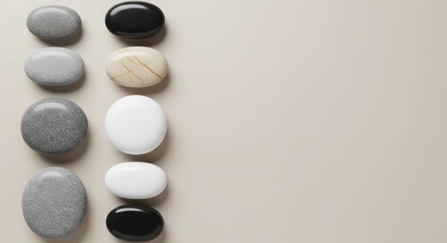 Polished pebbles in various shades of black, gray, and white are artistically aligned on a neutral surface creating a clean wellness design. photo