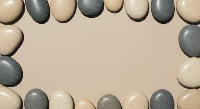 Frame of smooth gray and beige pebbles surrounds a neutral background, perfect for a zen, spa, or wellness themed graphic design element. photo