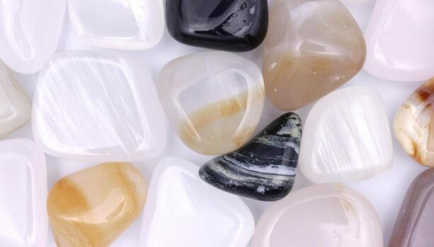 Polished agate stones in various colors and patterns are scattered randomly on a white surface creating a textured and decorative display. photo