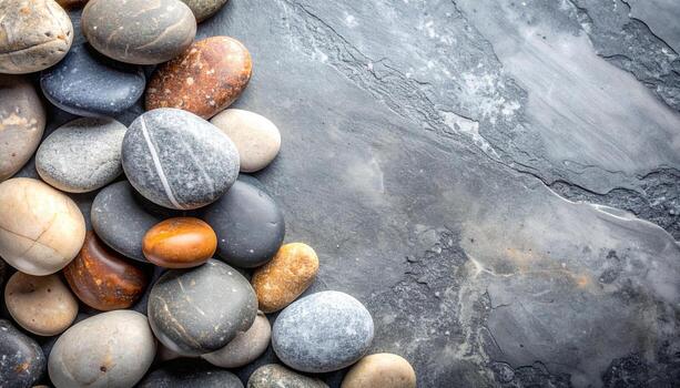Smooth colorful pebbles are arranged on a textured slate surface creating a natural and calming spa like aesthetic composition. photo