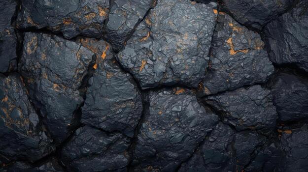 Close up of dark gray rough rock texture surface with cracked patterns and small bits of orange oxidation providing a geological background. photo