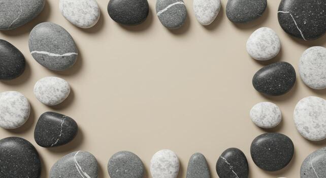 A calming frame of smooth grey pebbles and stones border a beige background creating a natural spa like zen decoration or artistic template. photo