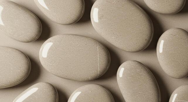 Multiple smooth, flat, oval-shaped stones are displayed in a close-up, full-frame view, arranged randomly with subtle natural lighting. photo