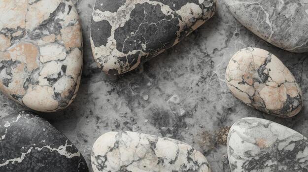 Collection of smooth natural stones with unique black and tan mottled patterns are arranged on a textured gray surface background. photo