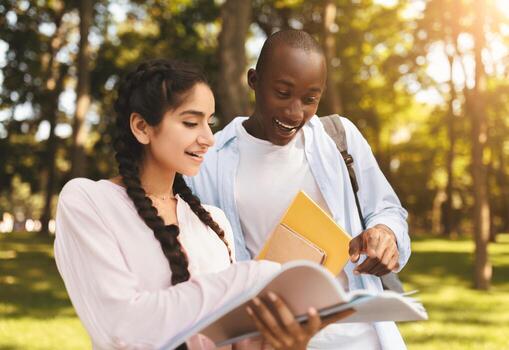 Learning concept. Multiracial student guy and lady preparing for classes, studying with books in university campus outdoors, having rest and walking outside photo