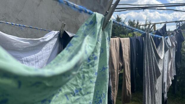 washed clothes and linens are drying on a line outside photo