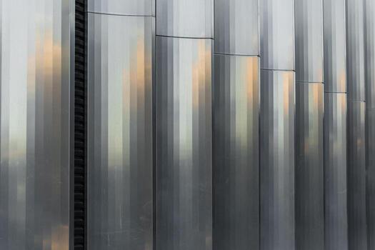 Vertical corrugated metal panels with a reflective surface, create a geometric industrial pattern. Suitable for backgrounds, architecture presentations, and construction industry visuals. photo