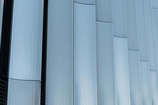 Closeup of a modern building facade with vertical metallic panels and repeating geometric pattern. For illustrating architecture, construction, or urban design concepts in presentations and publications. photo