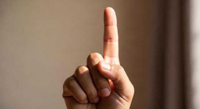 Close up of a Hand with Index Finger Pointing Upwards Symbolizing One Number One Success or a Great Idea photo