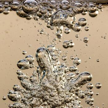 Close up abstract view of numerous air bubbles rising through a golden liquid creating dynamic textures and patterns photo