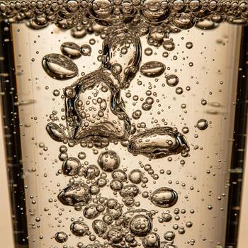 Close up macro shot of effervescent bubbles rising rapidly through clear liquid in a glass creating a dynamic texture photo