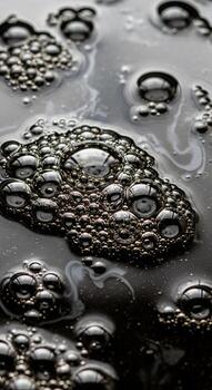 Macro view of dark liquid surface with clusters of reflective bubbles and swirling patterns photo