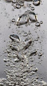 Close up of shimmering water surface with numerous small and large bubbles rising and bursting in abstract patterns photo