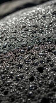 Close up macro view of a textured dark gray surface with subtle highlights reflecting light photo